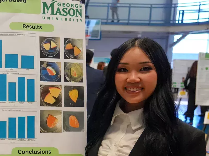 Student standing next to their research project